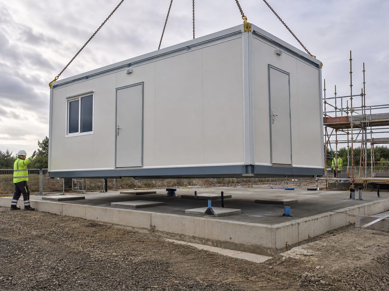 Sandwich panel container placement with crane lifting, base support, and utility connections