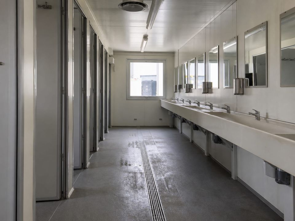 Toilet container corridor with washbasin run, mirrors, and central channel drainage