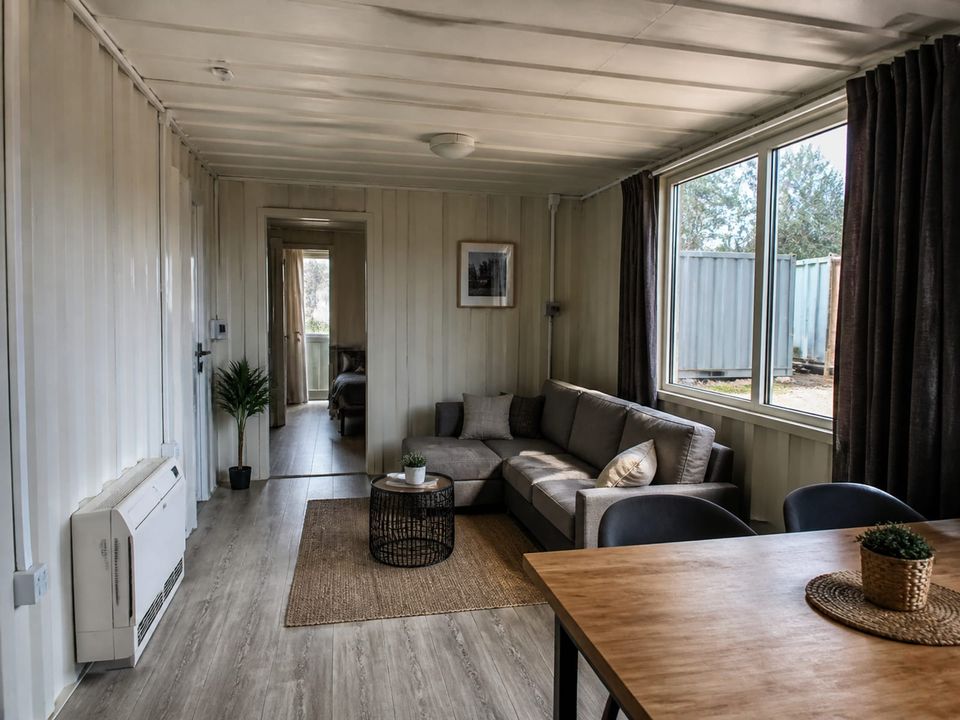 Container home living area with daylight, outlook, and compact furniture arrangement
