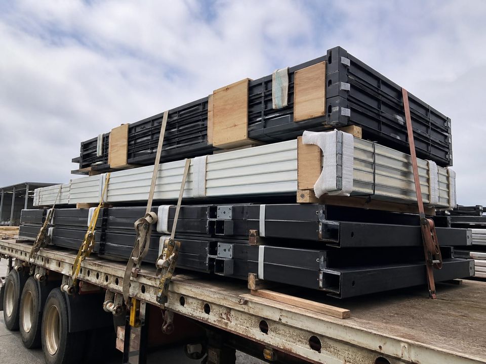 Flat-packed container components stacked and restrained for transport