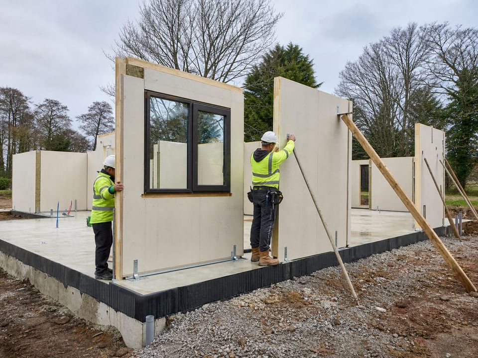 Prefab wall panels being erected on a prepared foundation