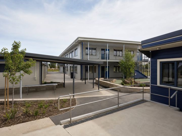 Prefabricated school building with classroom windows and a paved circulation area