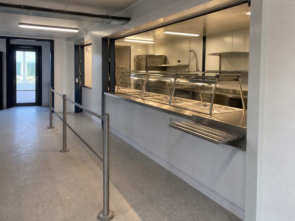 Cafeteria container service counter with tray flow and queue space