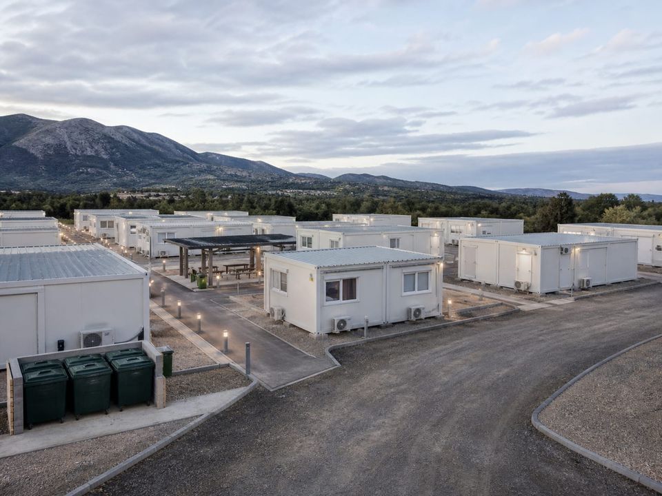 Disaster shelter settlement with unit spacing, lit pathways, and communal facilities