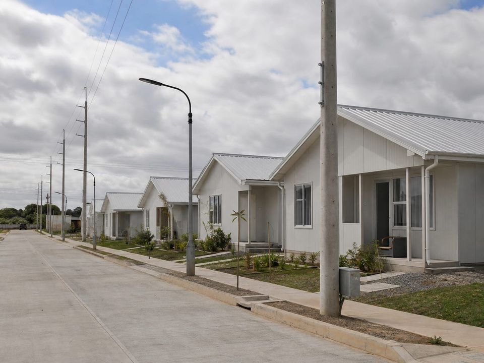 Rehousing settlement street with lit footpaths, parking, and defined plot boundaries