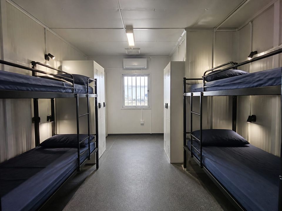 Dormitory container shared room with bunk beds, lockers, and circulation space