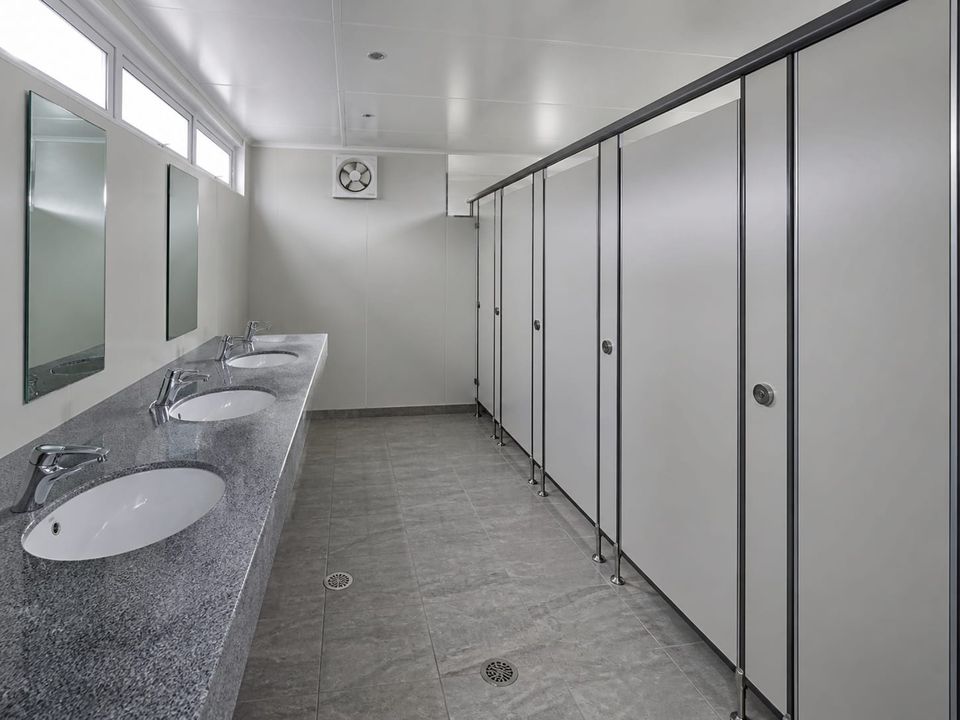 Prefab WC block interior with cubicles, washbasins, and wash-down floor drainage